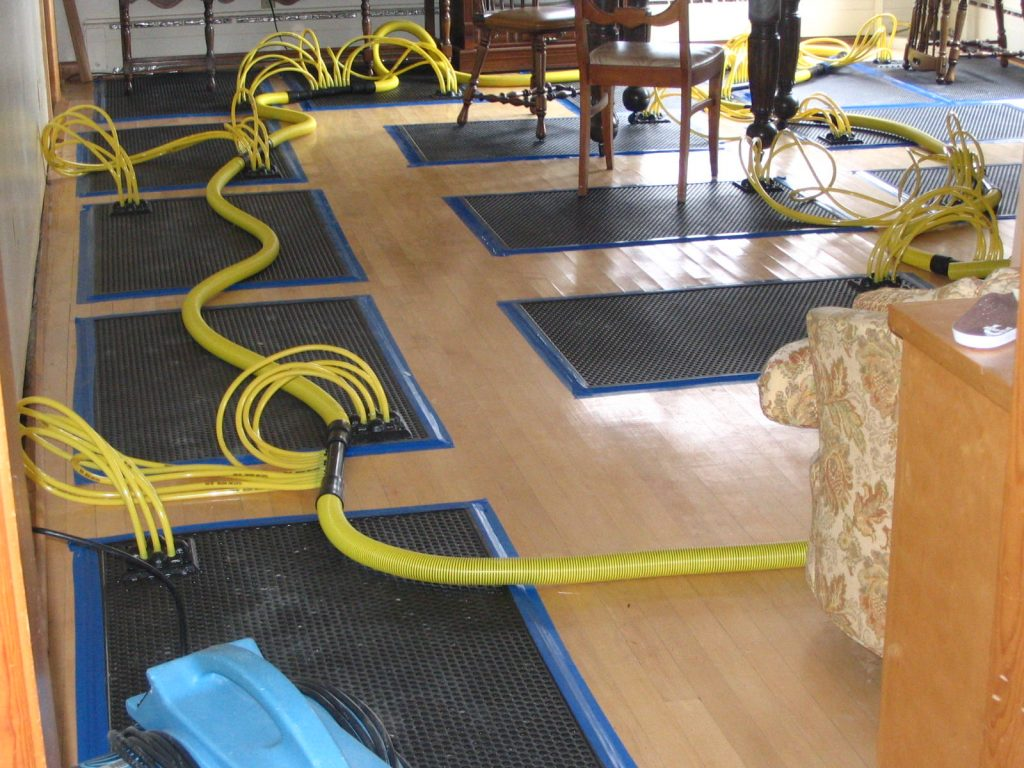 Floor drying mats and dehumidifiers set up for water extraction